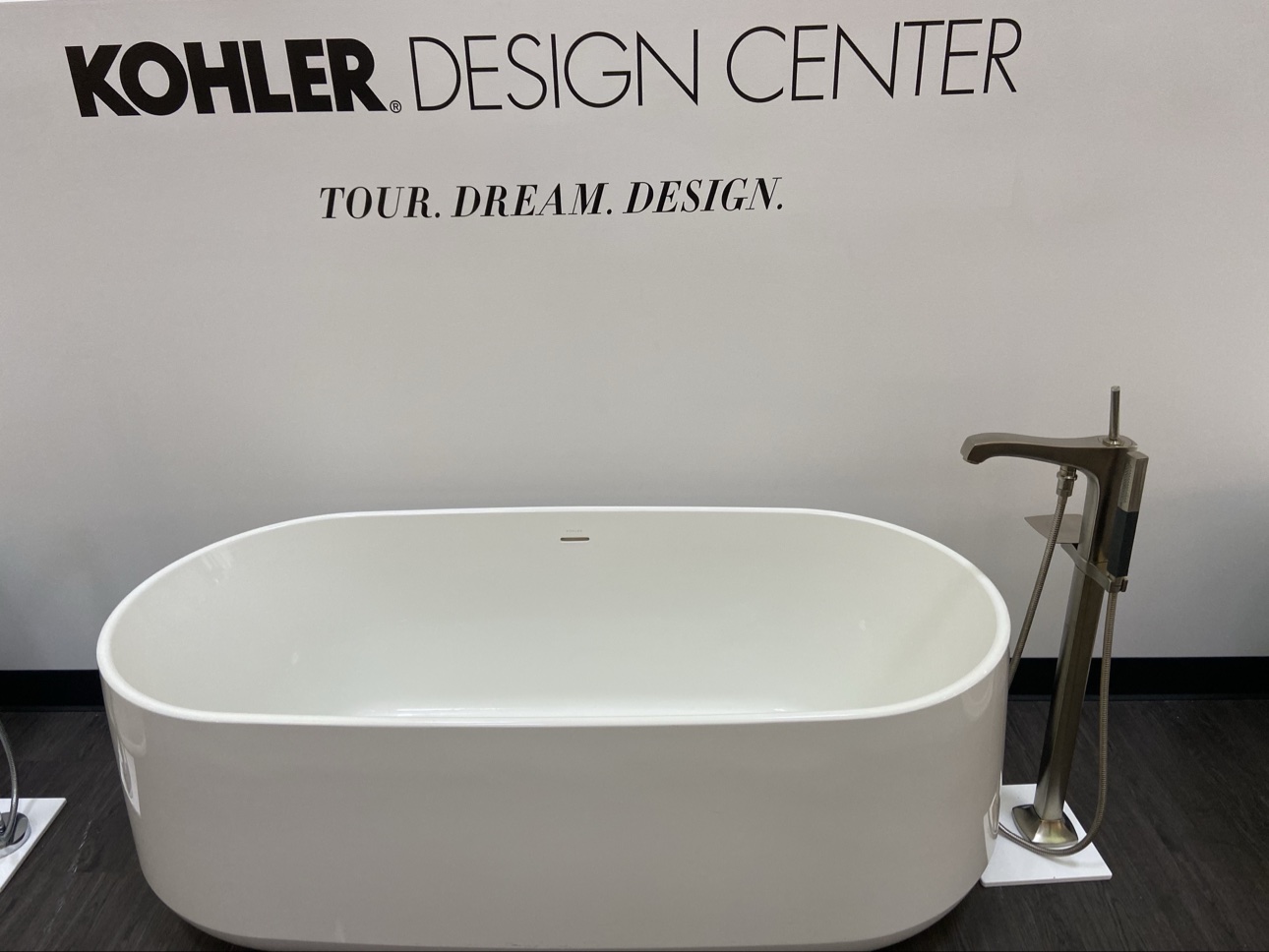Freestanding Kohler bathtub under the Kohler Design Center's TOUR. DREAM. DESIGN. wall