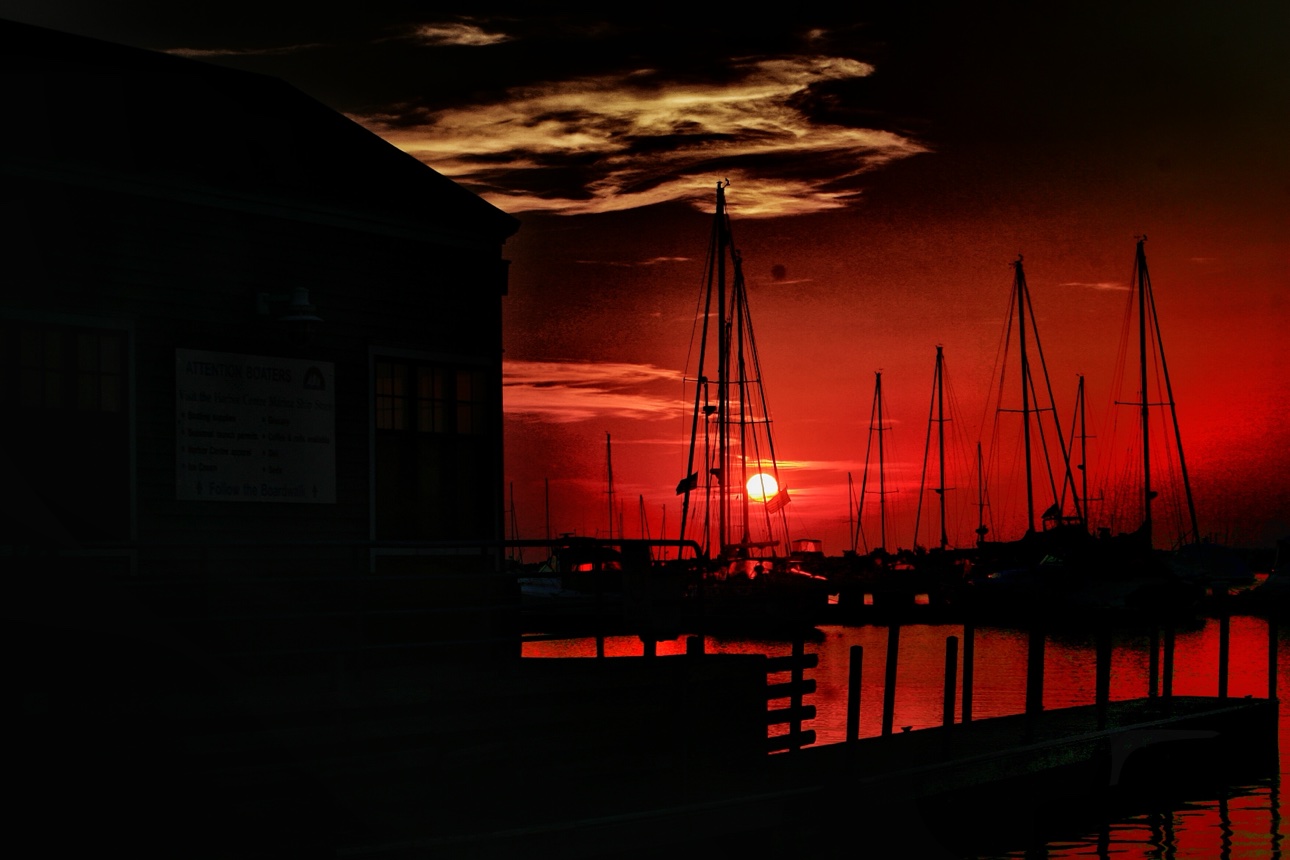 Sailboat masts silhouetted against a red sunset at the marina