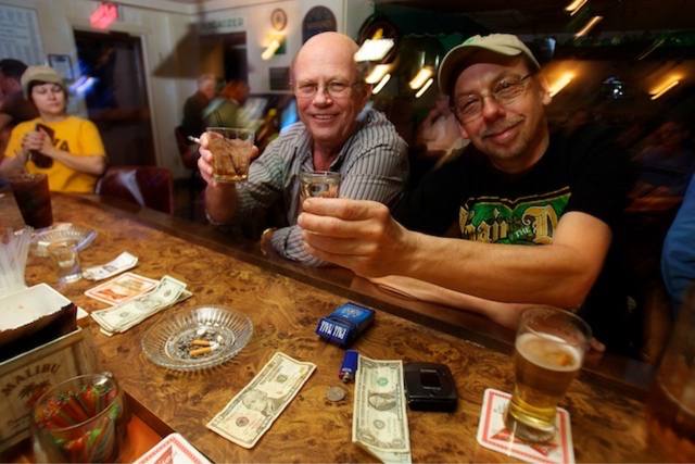 two men toasting at the bar, cash on the wood, Malibu box