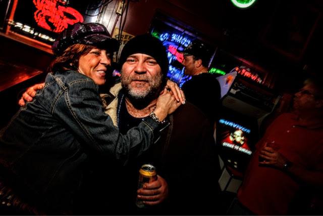 woman hugging a bearded man, neon signs, Survivor arcade game (near-duplicate pair