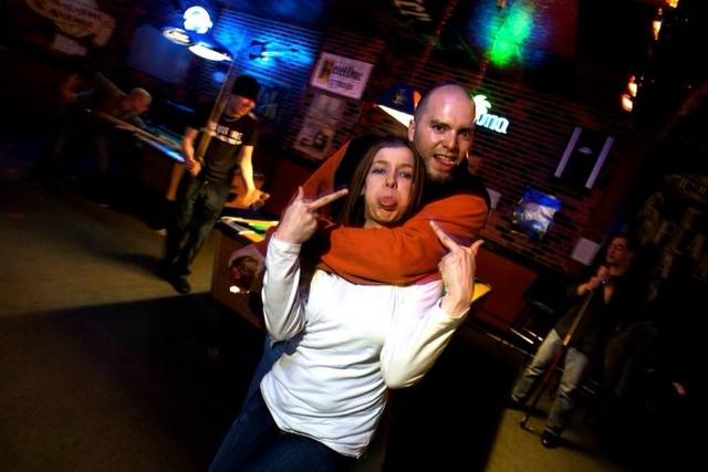couple posing by the pool table, brick walls