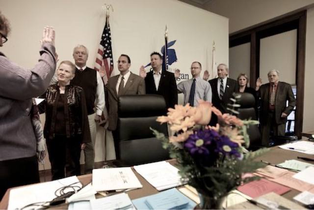 the council being sworn in, hands raised