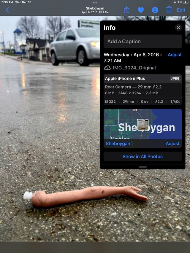 iPhone info-panel screenshot of a Barbie doll arm on wet Sheboygan pavement (Apr. 6, 2016