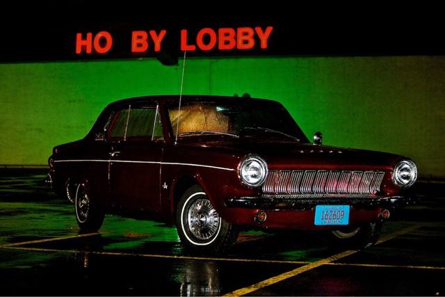 red classic Dodge at night under the "HO BY LOBBY" (Hobby Lobby) sign, two angles