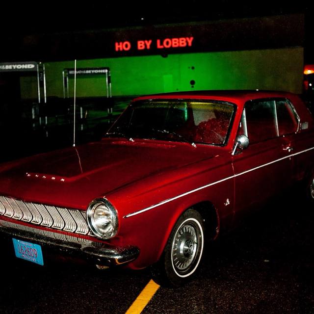 red classic Dodge at night under the "HO BY LOBBY" (Hobby Lobby) sign, two angles