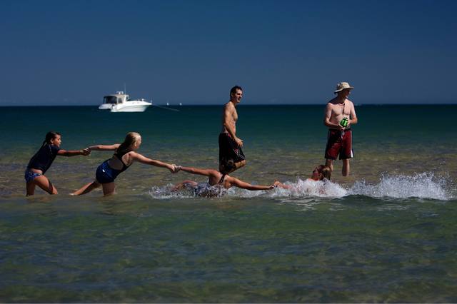 kids holding hands in the surf, girls splashing in the waves