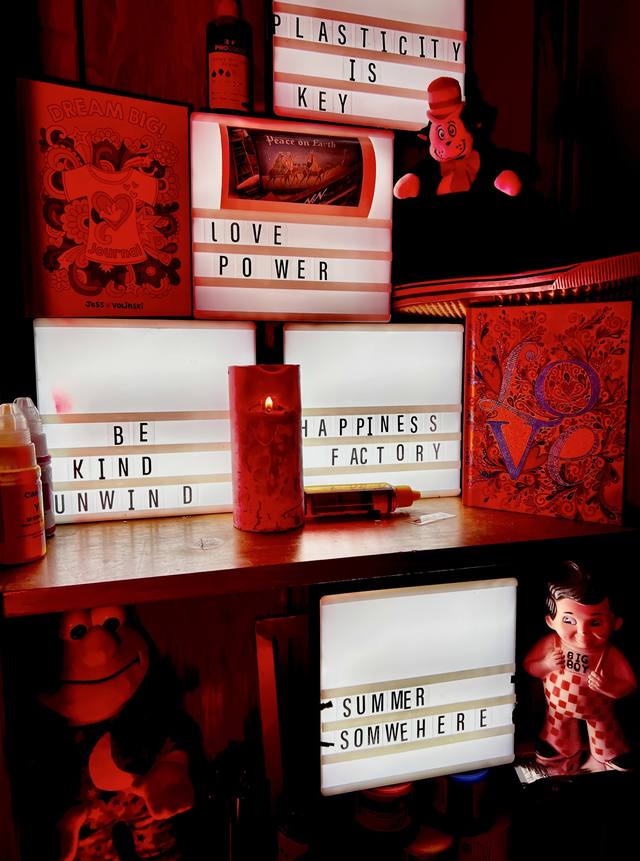 light-box wall: "PLASTICITY IS KEY," "LOVE POWER," "BE KIND UNWIND," "HAPPINESS FACTORY," "SUMMER SOMWEHERE," Dream Big journal, Big Boy figure