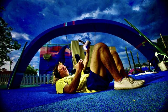 Mike lying on the blue playground arch, holding a projector lamp