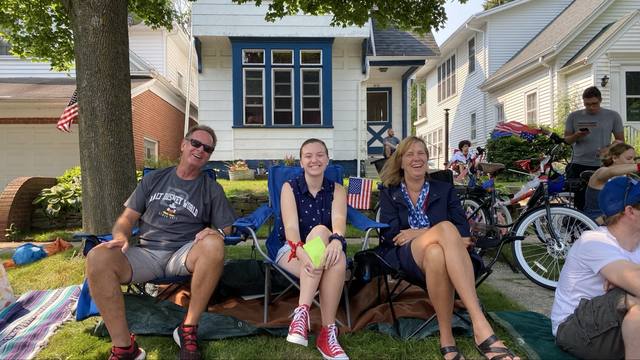 family on a lawn watching, flags, decorated bikes