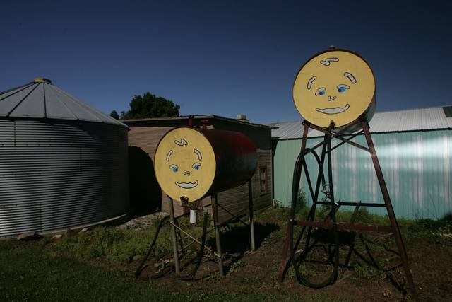 six angles of two fuel/oil tanks painted with smiley faces on a farm (silo, barn, one shot from a car window