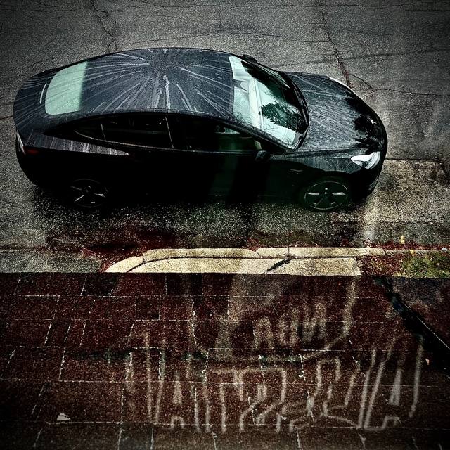 Tesla in the rain, brick street, shot from above