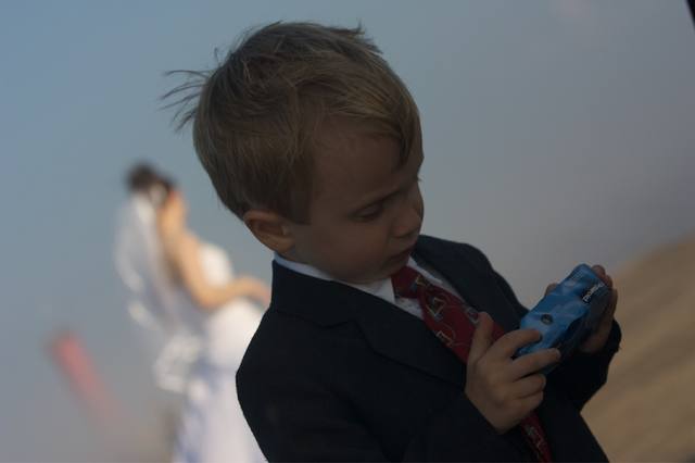 The ring-bearer with a disposable camera, bride soft in the background