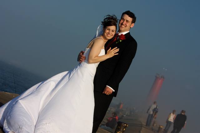 Embrace on the pier — lake on one side, lighthouse on the other